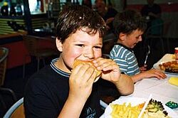 Ein Junge beißt in einen Hamburger Ein Junge beißt in einen Hamburger