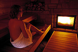 Frau vor dem Kamin in der Maa-Sauna Frau vor dem Kamin in der Maa-Sauna